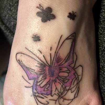 Customer’s butterfly tattoo work: large gradient purple-pink butterfly + small black butterflies on wrist/foot, fresh glossy appearance of the client’s personalized tattoo
