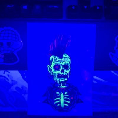 UV blacklight-activated glow effect of the same punk zombie tattoo (fluorescent tattoo ink on practice skin) – bright luminous display in dark conditions